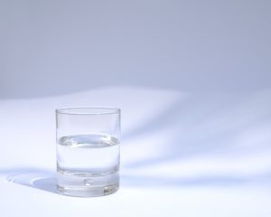 an 8oz water glass filled halfway on a white background with grey shadows