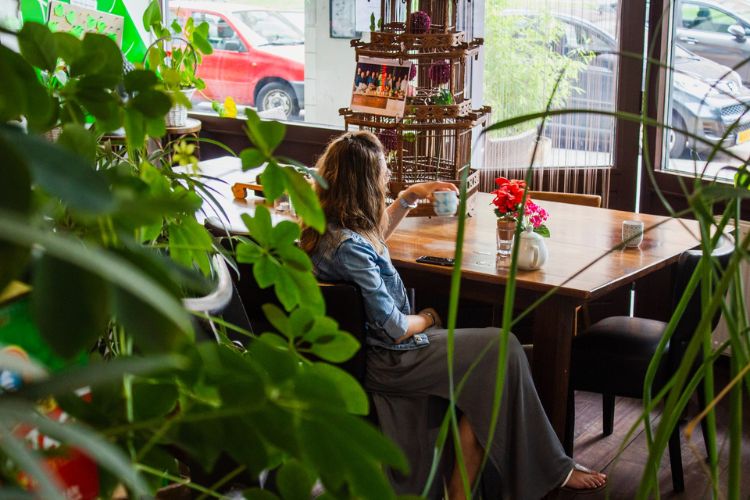woman sitting at a table, surrounded by plants, drinking tea, in a situation where you could need visual vestibular integration